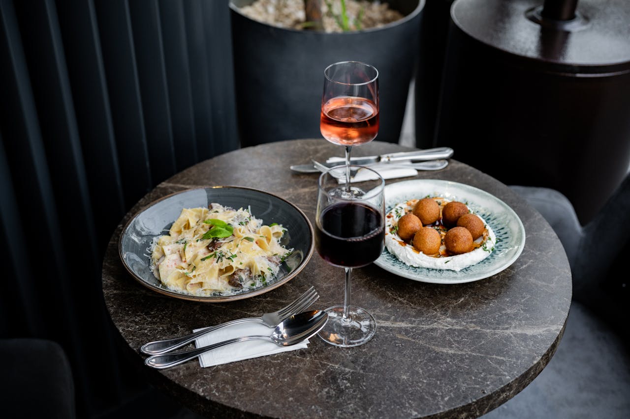 A table with two plates of food and a glass of wine